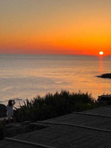 une femme regarde le coucher du soleil sur l'océan dans l'établissement Villa calypso Pantelleria, à Pantelleria