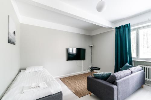 1 dormitorio con cama, sofá y TV en Spot Apartments Hyrylä, en Hyrylä