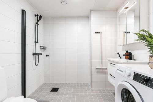 y baño blanco con ducha y lavadora. en Spot Apartments Hyrylä, en Hyrylä