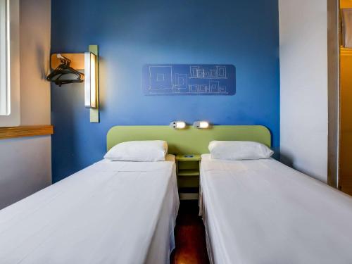 two beds in a room with a blue wall at ibis budget Rio de Janeiro Nova America in Rio de Janeiro