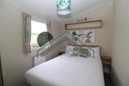 a bedroom with a white bed and a window at Serenity - 8 Berth 3 Bedroom Static Caravan in Heysham