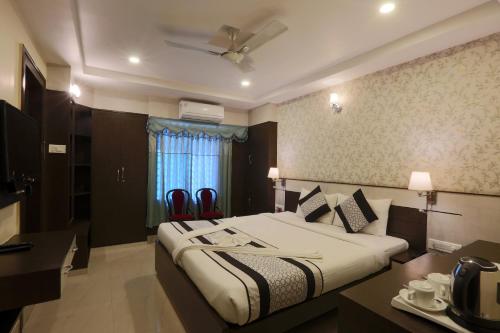 um quarto de hotel com uma cama, uma mesa e cadeiras em Hotel Blue Bird, Nagaon em Nowgong