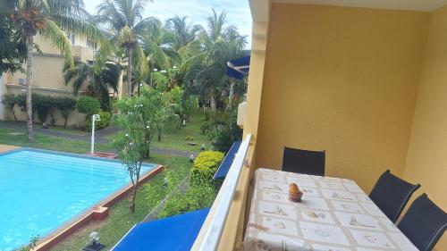 a balcony with a table and a swimming pool at Grenadier A in Flic-en-Flac