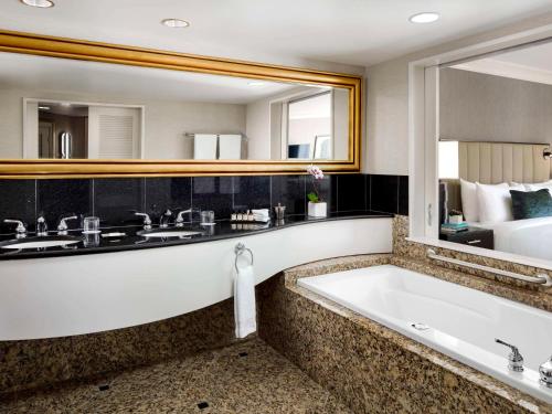 a bathroom with a tub and a large mirror at Fairmont Vancouver Airport In-Terminal Hotel in Richmond