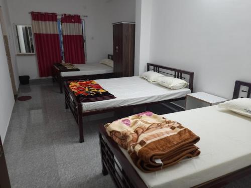 a room with three beds in a room at Banpalashi Inn in Jhārgrām
