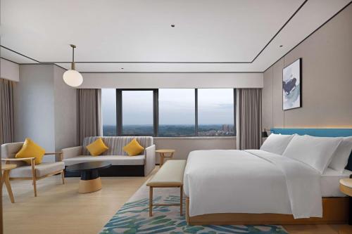a bedroom with a bed and a living room at Hilton Garden Inn Zigong High-Tech Zone in Zigong