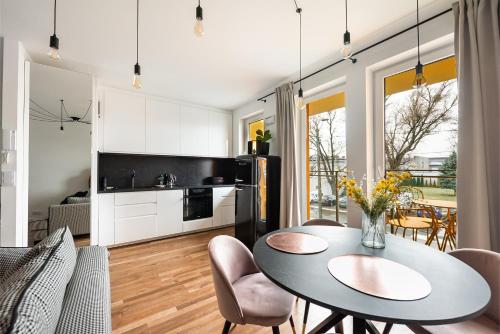 Ursynów Kłobucka Cosy Apartment في وارسو: مطبخ وغرفة طعام مع طاولة وكراسي