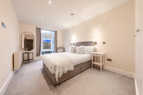 a white bedroom with a large bed and a window at Candler Mews - Twickenham in Twickenham