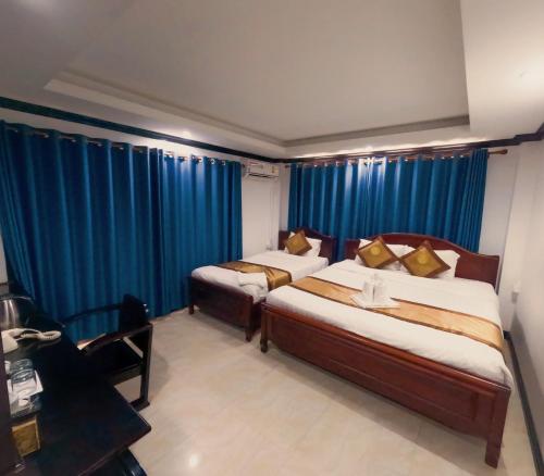 two beds in a room with blue curtains at Vang Vieng Consiana Hotel in Vang Vieng