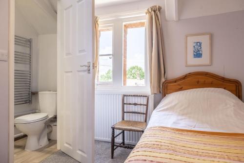 a bedroom with a bed and a toilet and a window at The Old Coach House C in Grimston