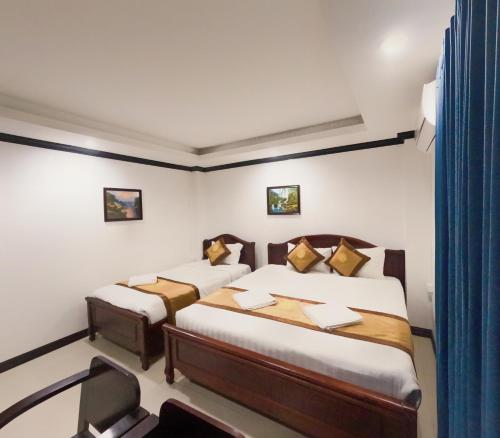a bedroom with two beds and a blue curtain at Vang Vieng Consiana Hotel in Vang Vieng