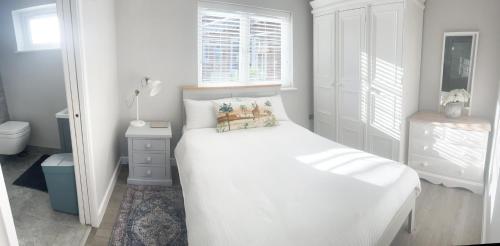 a white bedroom with a bed and a window at The Studio @ Michael House in Horley