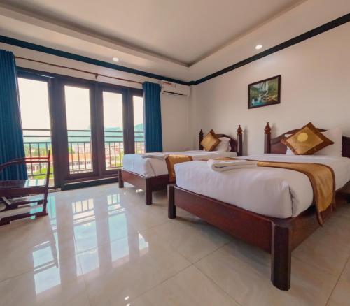 um quarto com 2 camas e uma grande janela em Vang Vieng Consiana Hotel em Vang Vieng