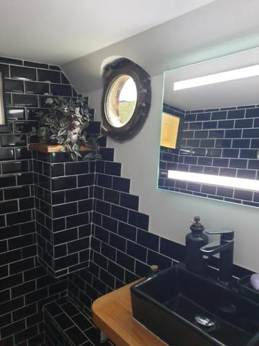 a black tiled bathroom with a sink and a mirror at Peniche C'est La Vie in Les Grésillons