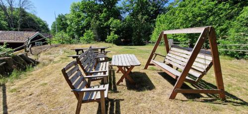 two wooden benches and a table in a field at Långasjönäs Camping & Stugby in Karlshamn