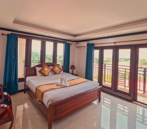 a bedroom with a bed with blue curtains and windows at Vang Vieng Consiana Hotel in Vang Vieng