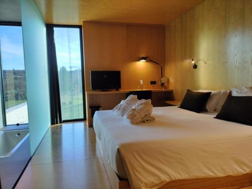 a hotel room with two beds and a large window at Cró Hotel Rural in Rapoula do Côa