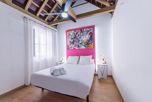 Un dormitorio con una cama blanca y una pintura en la pared en AlohaMundi Martínez Montañés en Sevilla