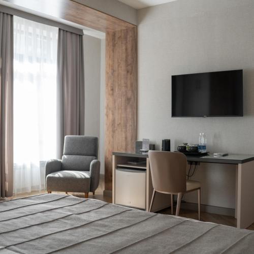 Una habitación de hotel con una cama, un escritorio y una silla. en Five Hotel, en Bishkek