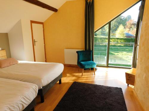 a bedroom with two beds and a blue chair and a window at Gites et Cocon des Puys in Nébouzat