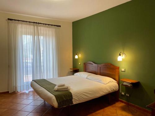 1 dormitorio con cama y pared verde en Mingone Hotel Ristorante, en Isola del Liri