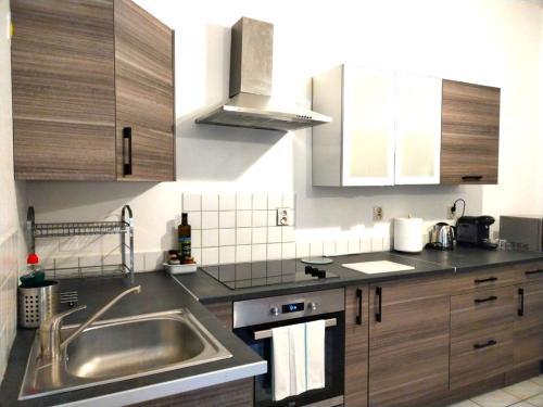 uma cozinha com um lavatório de aço inoxidável e armários de madeira em A Deux Pas des Halles - Hypercentre - Idéal Couple em Pau