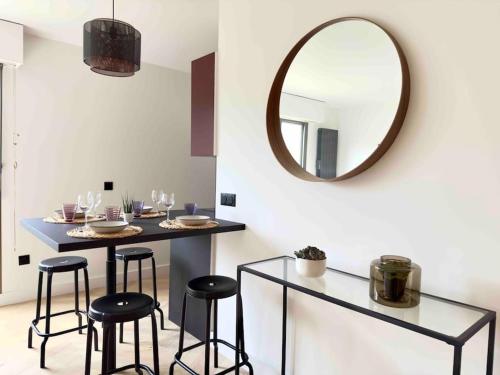 a dining room with a table with stools and a mirror at Charmant Appartement Neuilly - 10mn Champs-Elysées in Neuilly-sur-Seine