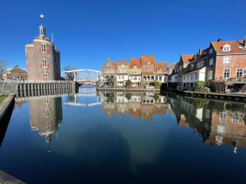 a river in a city with buildings and a clock tower at Chalet Sunrise Vierte Reihe Haus Nr 218 in Enkhuizen