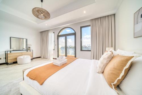 a white bedroom with a large bed and windows at Frond D Villa, Palm Jumeirah - Mint Stay in Dubai