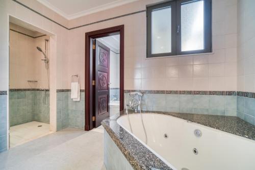 y baño grande con bañera y ducha. en Frond D Villa, Palm Jumeirah - Mint Stay, en Dubái