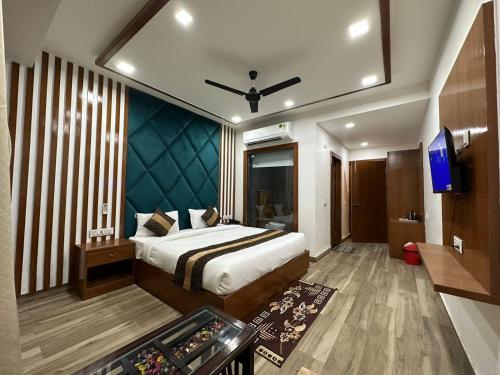 アグラにあるHotel The Rich Grand Agraのベッドとテレビが備わるホテルルームです。