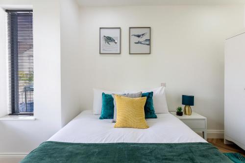 Dormitorio blanco con cama con almohada amarilla en Stunning West London W7 Modern Huge place 4bed 2 bath with garden free parking (7 occupancy), en Londres
