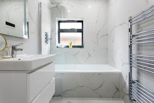 a white bathroom with a sink and a window at Stunning West London W7 Modern Huge place 4bed 2 bath with garden free parking (7 occupancy) in London