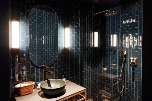 a bathroom with a sink and a shower with blue tiles at Bienheureux Hôtel & Restaurant in Wasquehal