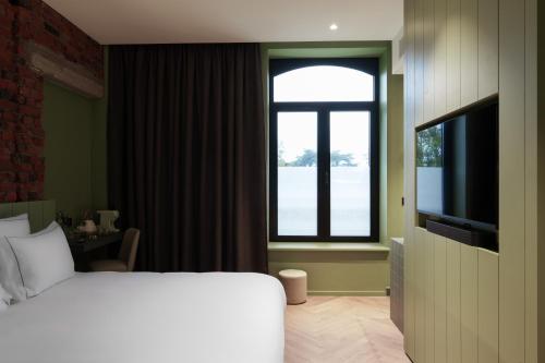 a hotel room with a bed and a window at Bienheureux Hôtel & Restaurant in Wasquehal