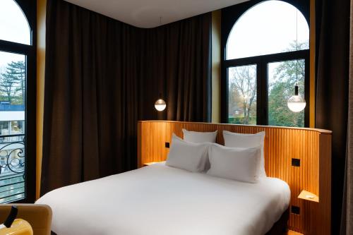 een slaapkamer met een wit bed en 2 ramen bij La Maison des Bienheureux in Wasquehal