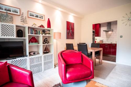 un salon avec une chaise rouge et une table dans l'établissement Les Aiguilles du Brevent - Grand Appt Renove - Central - Terrasse avec Vue, à Chamonix-Mont-Blanc