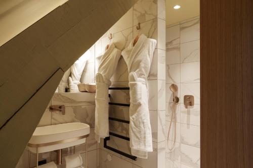 a bathroom with a shower and a sink and towels at Bienheureux Hôtel & Restaurant in Wasquehal
