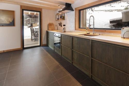 a kitchen with a sink and a large window at Chalet L'Oratoire - Huge Garden - Renovated Historic Chalet with Mountain Views in Les Houches