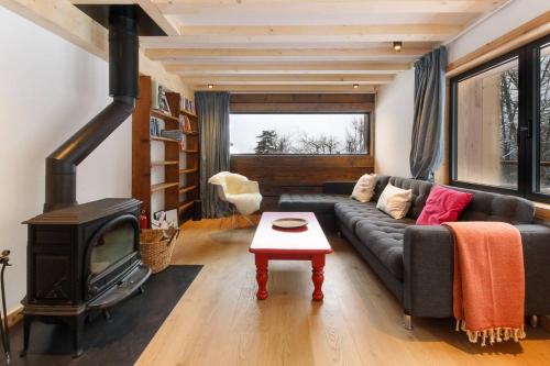 een woonkamer met een zwarte bank en een open haard bij Chalet L'Oratoire & Mazot - Renovated Historic Chalet - Huge Garden & Separate Cabin for 2 in Les Houches