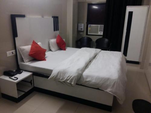 a bedroom with a white bed with red pillows at Hotel Shiva Haridwar - nearby bus and railway station in Haridwār
