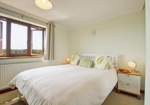茅根海岸的住宿－The Buoys，白色的卧室设有一张大床和一个窗户