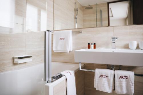 a bathroom with a sink and a mirror and towels at Hotel Arte in St. Moritz