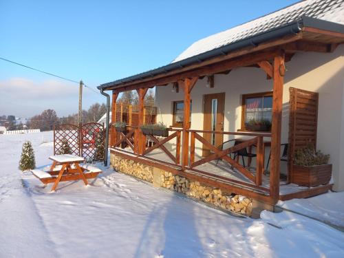 a house with a deck in the snow at Domki POD STARĄ PODKOWĄ Limanowa Nowy Sącz Kraków in Limanowa