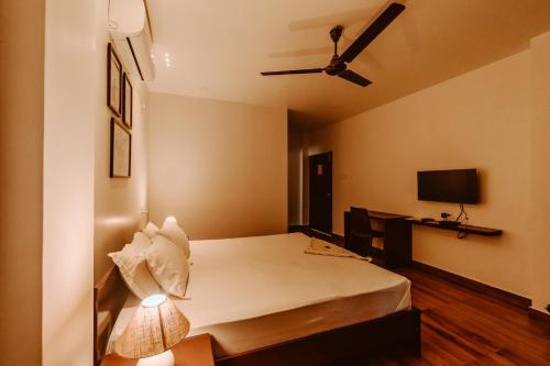 Cette chambre comprend un lit et un ventilateur de plafond. dans l'établissement Dibrugarh Tea Residency, à Dibrugarh