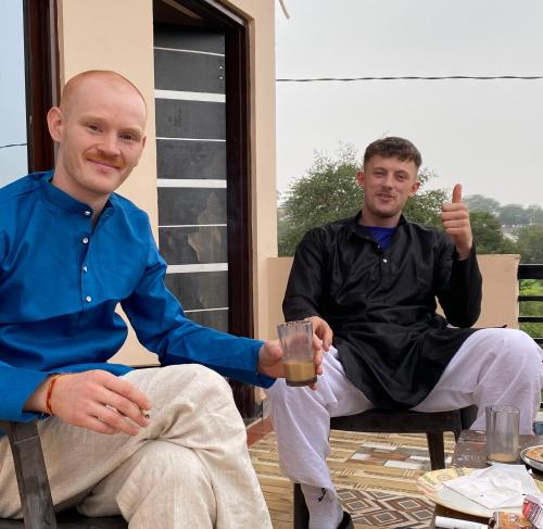 deux hommes assis sur une chaise avec un verre de bière dans l'établissement the natural view pushkar, à Pushkar