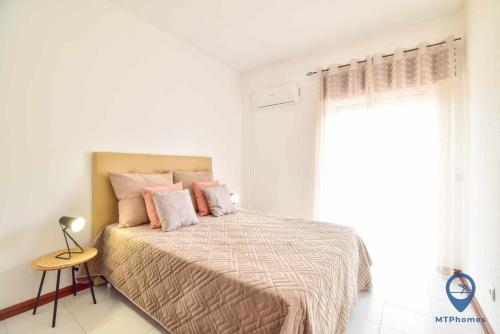a bedroom with a bed with pink pillows and a window at Apartamento 2 quartos e Piscina in Olhos de Água