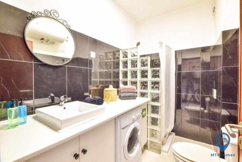 a bathroom with a sink and a washing machine at Apartamento 2 quartos e Piscina in Olhos de Água