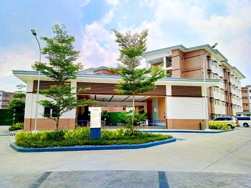 a building with two trees in front of it at Ace That Condo Staycation Cheer Residences beside SM Marilao in Marilao