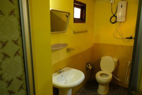 a yellow bathroom with a toilet and a sink at MENAKA HOMESTAY in Tangalle